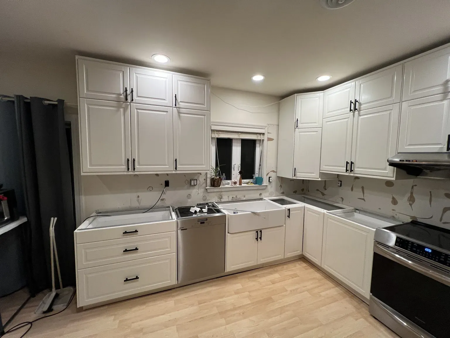White U-shaped IKEA kitchen with black handles and farmhouse sink